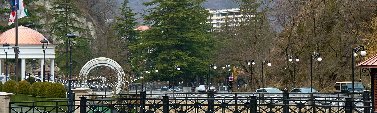 A scenic view of a park with a gazebo, a metal structure, and a church tower